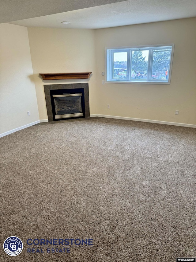 unfurnished living room featuring a tiled fireplace and carpet