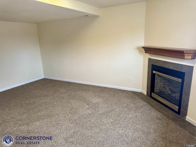 unfurnished living room with a tile fireplace and dark colored carpet