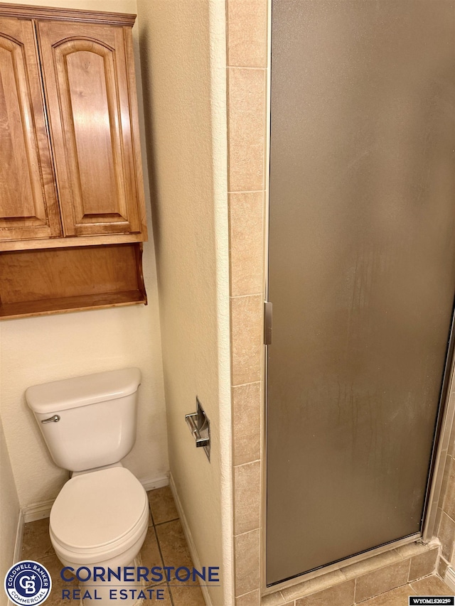 bathroom featuring tile patterned floors, toilet, and a shower with shower door