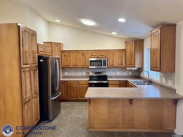 kitchen with sink, appliances with stainless steel finishes, decorative backsplash, vaulted ceiling, and kitchen peninsula