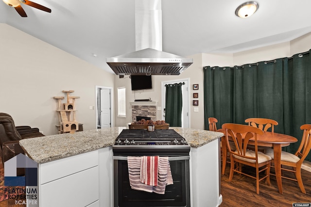 kitchen featuring white cabinetry, stainless steel range with gas stovetop, ventilation hood, a fireplace, and dark hardwood / wood-style flooring