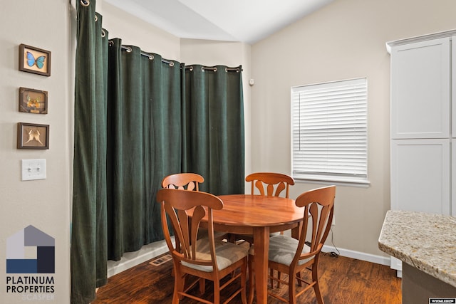 dining room featuring dark wood-type flooring and vaulted ceiling