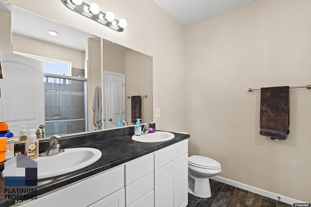 bathroom with hardwood / wood-style flooring, vanity, toilet, and an enclosed shower