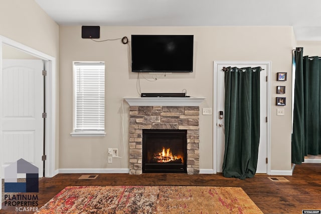 living room with dark hardwood / wood-style floors and a stone fireplace