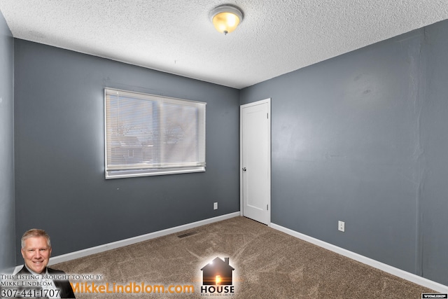 carpeted empty room featuring a textured ceiling