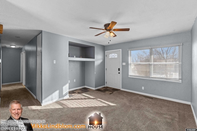 foyer with ceiling fan, dark carpet, and a textured ceiling