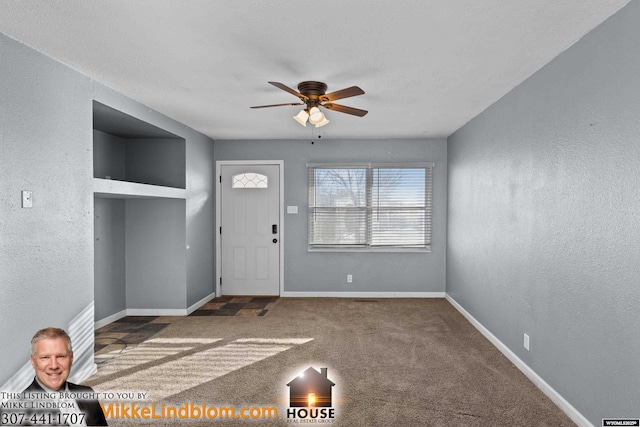 foyer featuring ceiling fan and carpet flooring