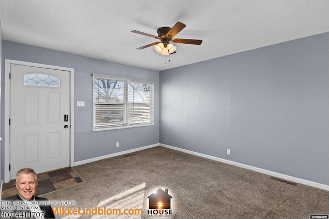 entrance foyer with ceiling fan and carpet