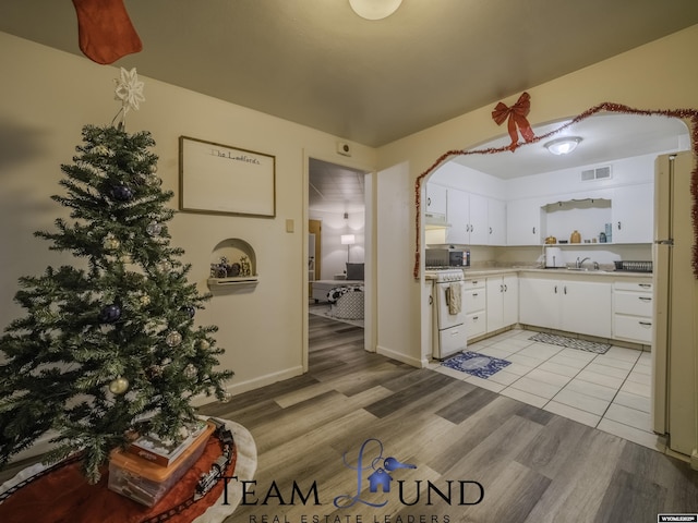 kitchen with sink, light hardwood / wood-style flooring, white appliances, range hood, and white cabinets