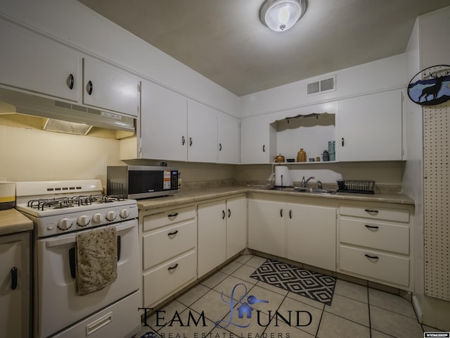 kitchen with white cabinets, sink, white gas stove, and light tile patterned flooring