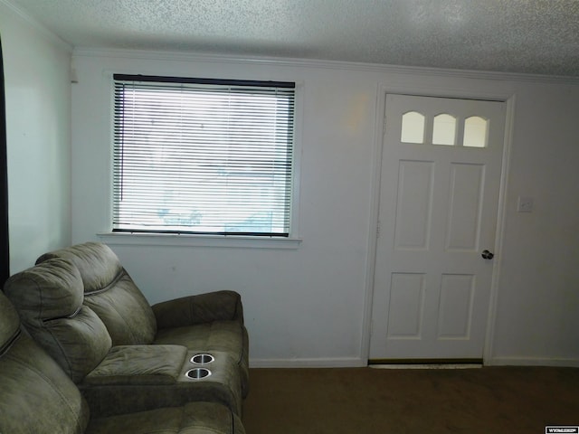 foyer with ornamental molding, a textured ceiling, and dark colored carpet