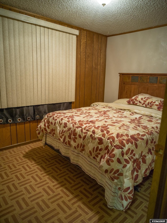 bedroom with parquet flooring, a textured ceiling, and wood walls