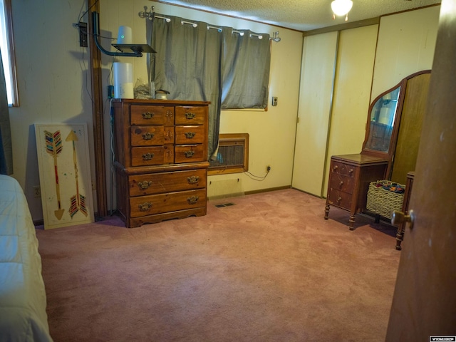 carpeted bedroom with heating unit and a textured ceiling