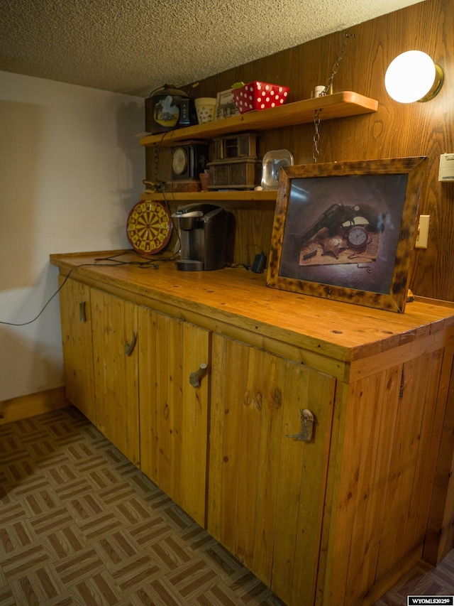 room details featuring wooden walls, a textured ceiling, and indoor bar