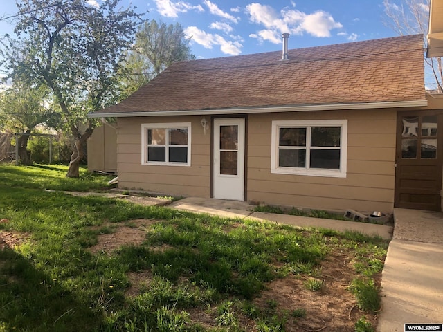 view of front of property with a shingled roof and a front yard