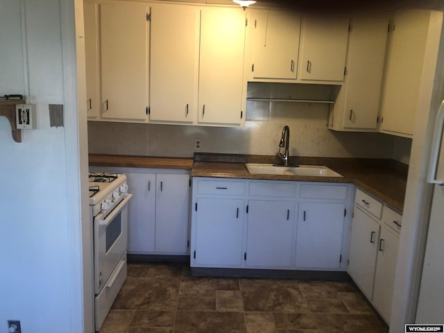 kitchen featuring dark countertops, white cabinets, and a sink