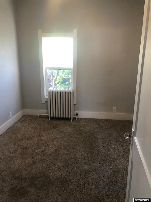 carpeted spare room featuring radiator heating unit and baseboards