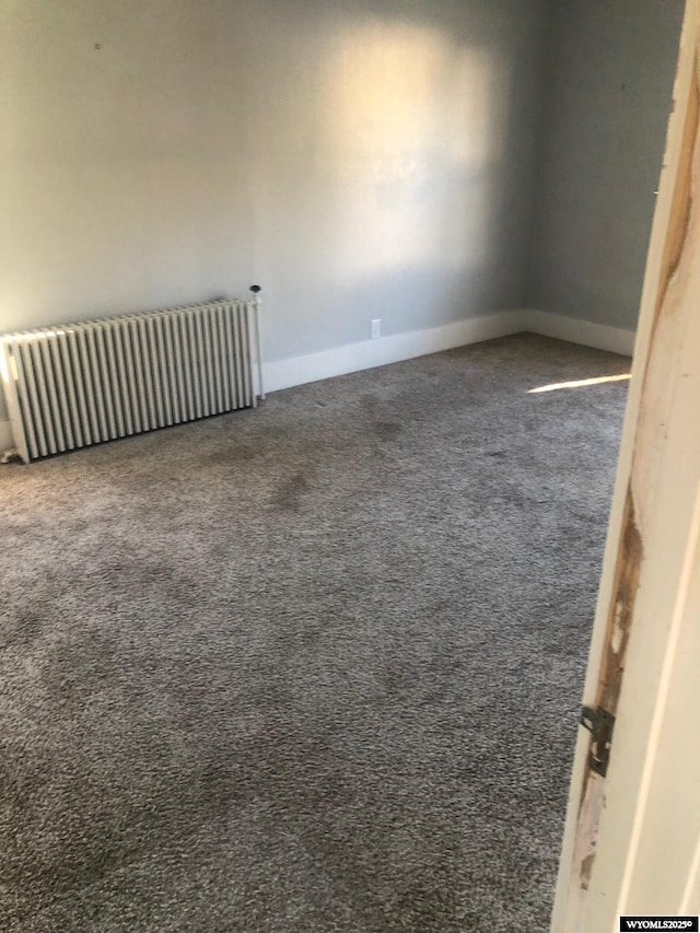 empty room with dark colored carpet and radiator