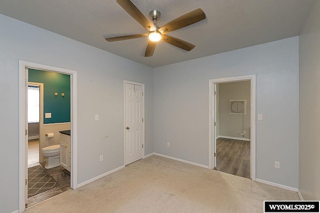 unfurnished bedroom with ceiling fan, ensuite bathroom, and carpet flooring