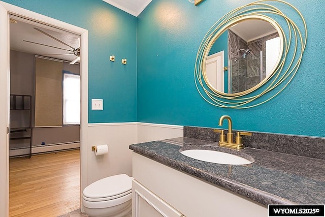 bathroom with hardwood / wood-style floors, a baseboard radiator, vanity, ceiling fan, and toilet