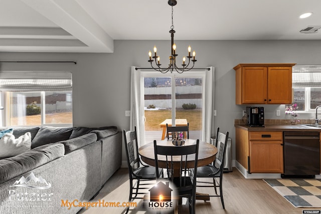 dining area with an inviting chandelier, sink, a wealth of natural light, and light wood-type flooring