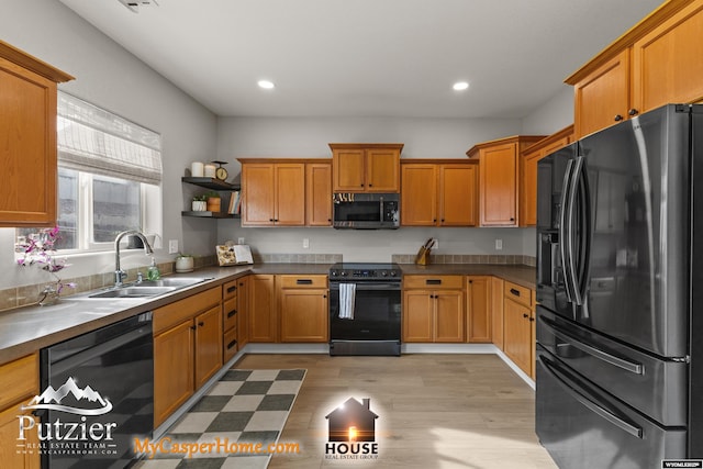 kitchen with sink, light hardwood / wood-style flooring, and black appliances