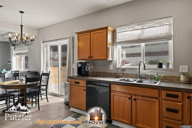 kitchen with sink, an inviting chandelier, hanging light fixtures, dishwasher, and light hardwood / wood-style floors