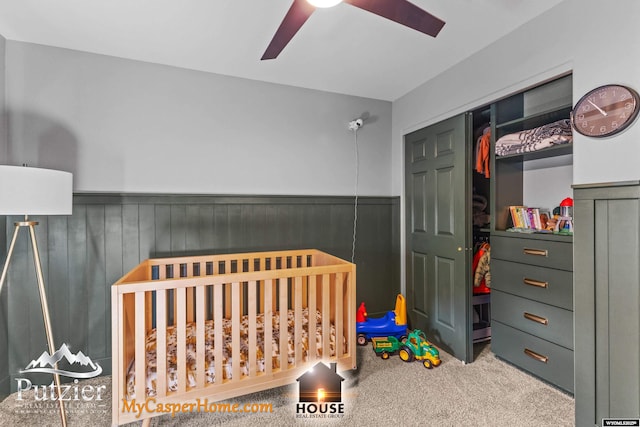 bedroom with ceiling fan, a closet, light carpet, and a crib