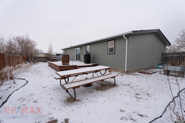 snow covered rear of property with a wooden deck