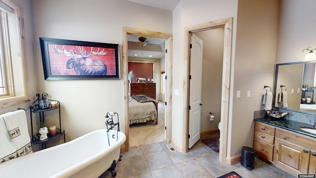 bathroom with a tub to relax in, toilet, vanity, and tile patterned flooring