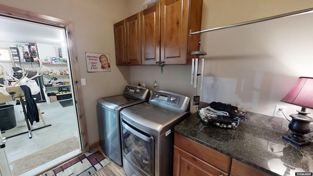 clothes washing area with separate washer and dryer and cabinets