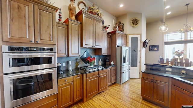 kitchen with stainless steel appliances, light hardwood / wood-style floors, sink, tasteful backsplash, and pendant lighting