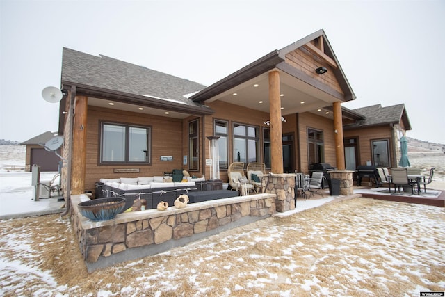 snow covered rear of property featuring a patio area and an outdoor living space