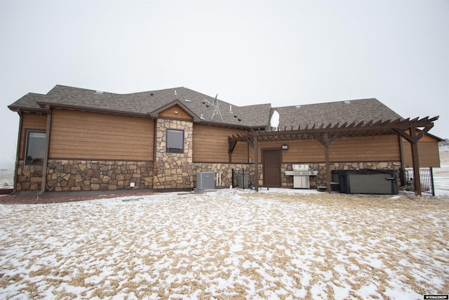 view of front facade with central air condition unit, a pergola, and a hot tub