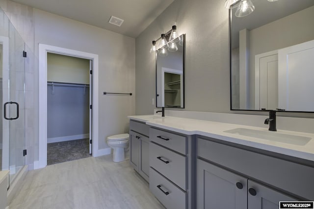 bathroom featuring toilet, vanity, and a shower with shower door