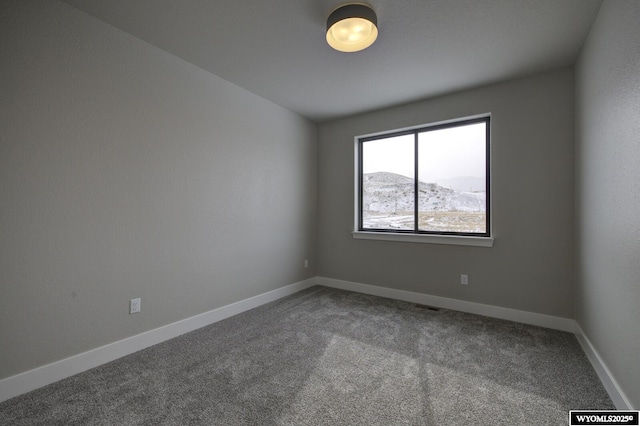 empty room featuring a mountain view and carpet flooring