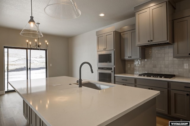 kitchen with a center island with sink, appliances with stainless steel finishes, sink, and gray cabinets