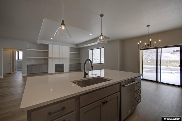 kitchen with sink, dark wood-type flooring, stainless steel dishwasher, and a kitchen island with sink