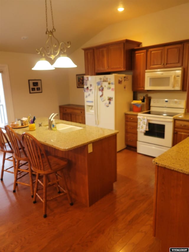 kitchen with an island with sink, hanging light fixtures, light stone countertops, sink, and white appliances