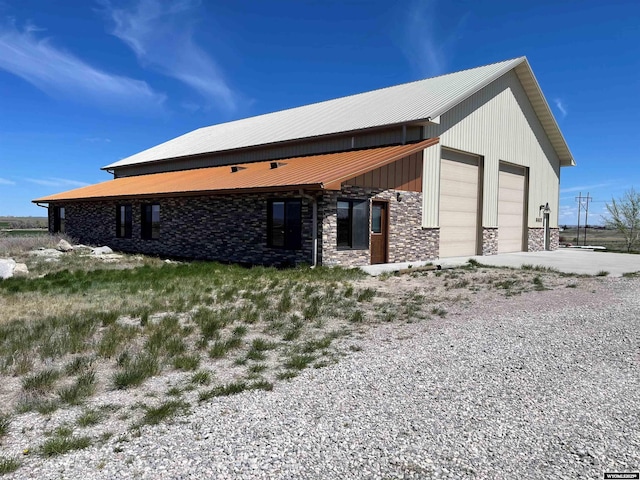 6447 Clark Cir, Torrington, WY 82240 - back of house featuring stone siding, metal roof, and a garage