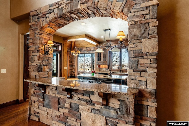 bar featuring light stone counters, stainless steel gas stovetop, dark hardwood / wood-style flooring, and pendant lighting