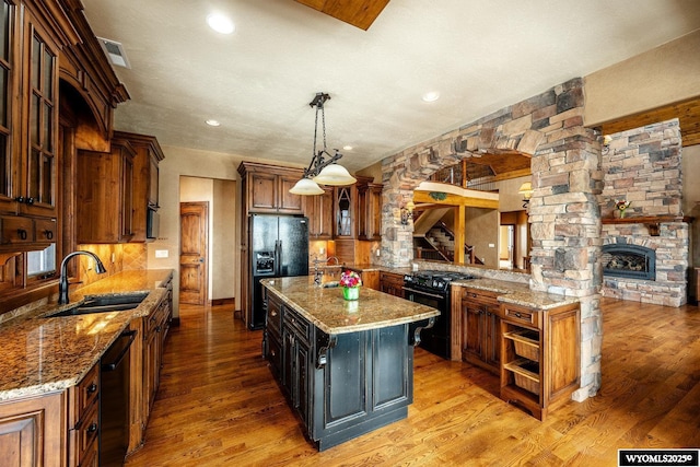 kitchen with sink, a center island, light wood-type flooring, decorative light fixtures, and black appliances