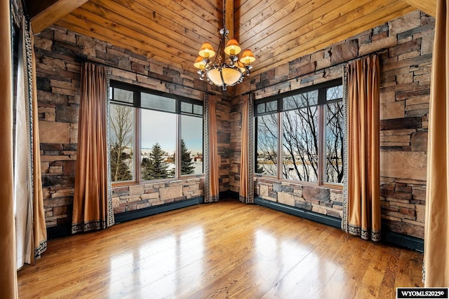 unfurnished dining area with light wood-type flooring, a notable chandelier, and wood ceiling