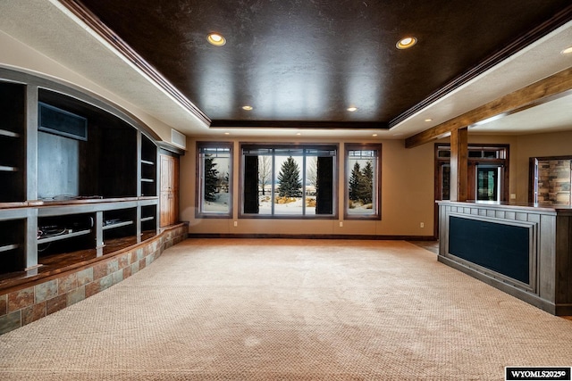 home theater room with a raised ceiling, light colored carpet, and built in features