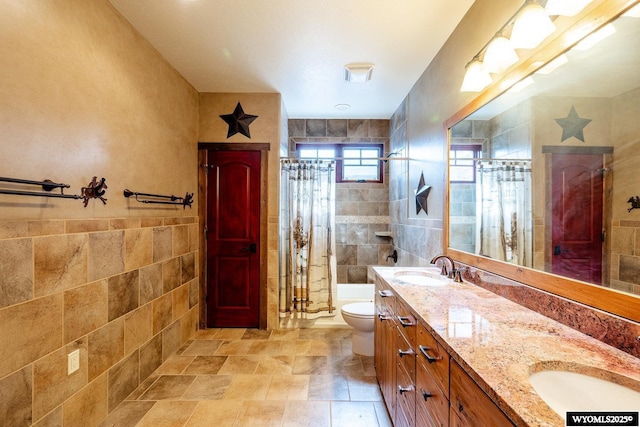 bathroom featuring tile walls, vanity, toilet, and walk in shower