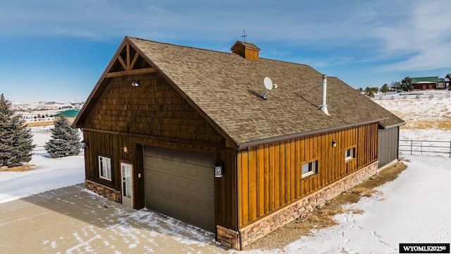 view of snowy exterior with a garage and an outdoor structure