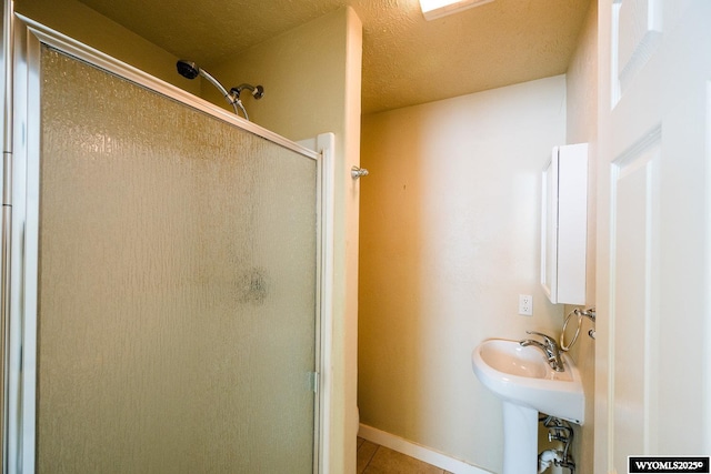 bathroom with tile patterned floors, a shower with shower door, and a textured ceiling