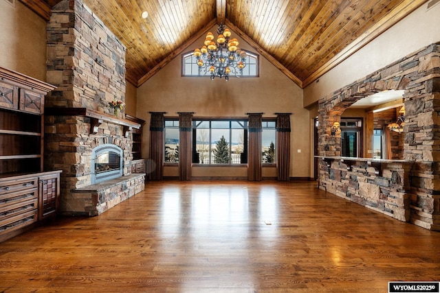 unfurnished living room with high vaulted ceiling, wood ceiling, hardwood / wood-style floors, a fireplace, and an inviting chandelier