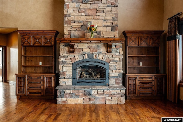 unfurnished living room with dark hardwood / wood-style flooring and a stone fireplace