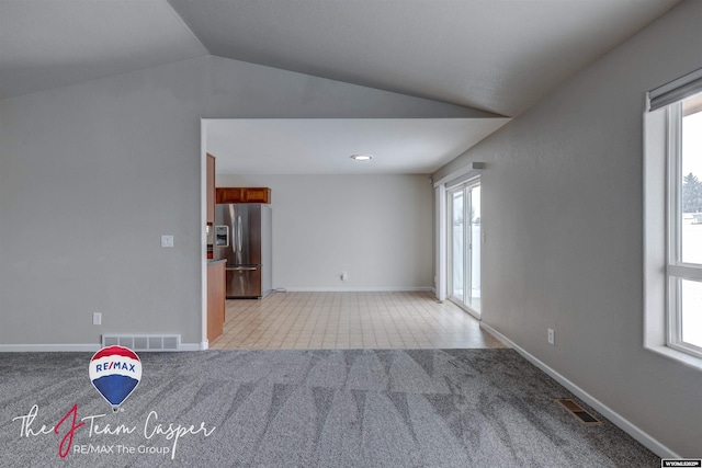 unfurnished room featuring vaulted ceiling and light colored carpet